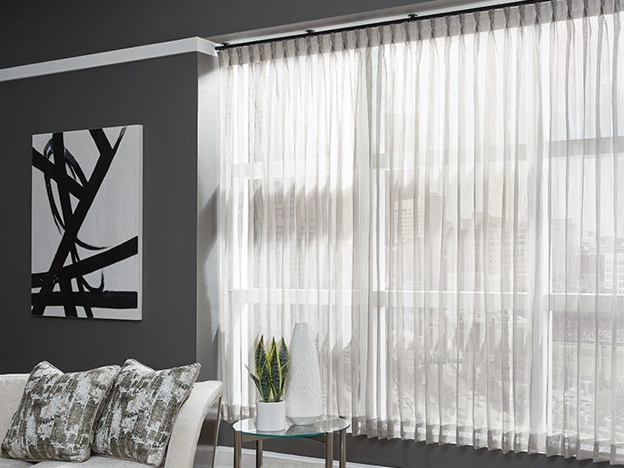 Modern living room with grey walls and large window with vertical drapery.